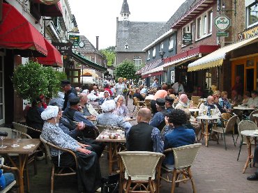 Het straatje. Op de voorgrond een dansgroep. Maar vooral trekharmonika’s.