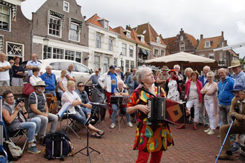 Theodora begeleidt zich zingend met de trekharmonica: haar meeslepend Nederlands populair repertoire trekt altijd veel enthousiast publiek.