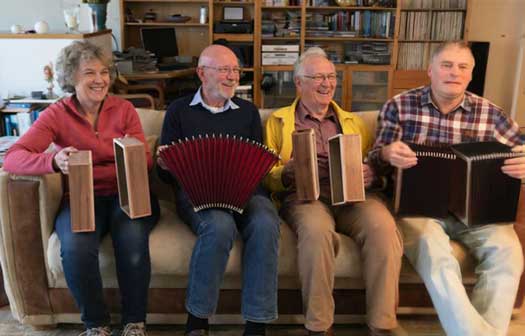 De vier bouwers: Anita Anita Ouddeken heeft de behuizing van de harmonica van de melodie kant en bas kant vast, Jan Jans een balg, Wim Vijfwinkel de kant van de behuizing van zijn harmonica en Jan Hoog Antink heeft twee balgen vast, maar het is niet duidelijk of hij die zelf heeft gemaakt.