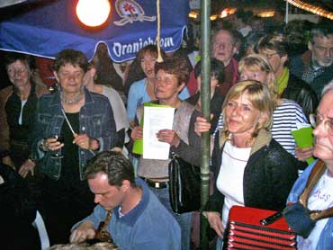 In de tent zingt het publiek zingt uit volle borst mee.