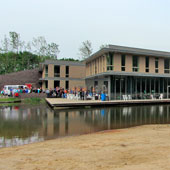 Een foto van het schoolgebouw, genomen vanaf de natuurtuin in wording (normaliter niet toegankelijk voor scholieren). De cateraar uit Kleef is net gearriveerd met zijn busje.