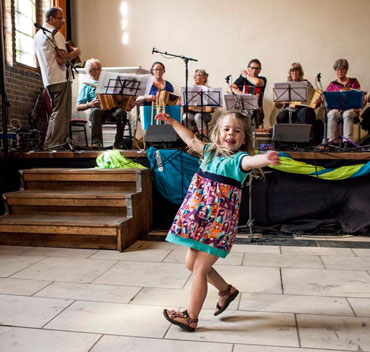 Een meisje danst vrolijk mee bij de presentatie van de workshop van Yann-Fach Perroches.